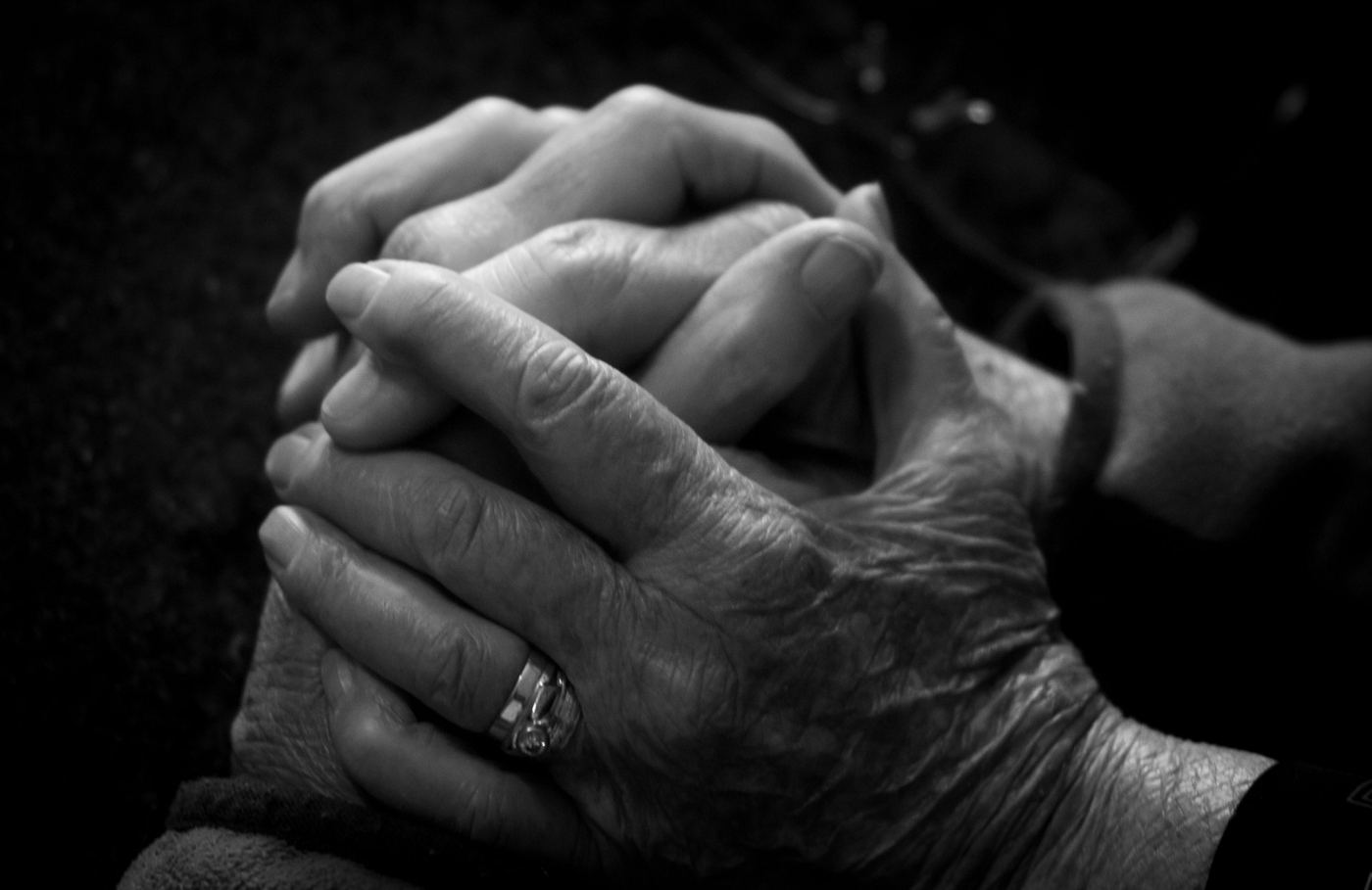 An older person's hands clasped with a younger person's hands